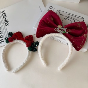 Detail of Christmas headband set with velvet red bows and festive sequins on white book
