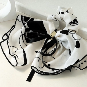 Detailed close-up of ink-wash ribbon scrunchie with elegant golden metal plate detail