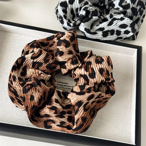 Macro view of leopard print hair scrunchies with pleated fabric texture in a tray
