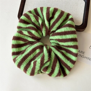 Close-up detail of green and brown striped wool knitted hair scrunchie with soft texture