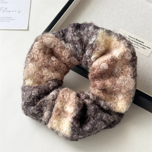 Macro detail of plush wool blend hair scrunchie with warm multi-color texture