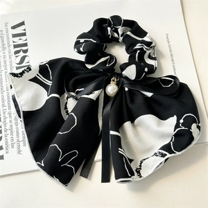 Detail of ink-style floral scrunchie with satin bow and elegant pearl pendant
