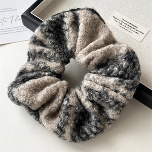 Close-up of oversized wool hair scrunchie with soft grey and beige textured plush fabric