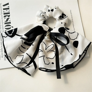 Detail of white ink floral scrunchie with a black silk bow and a white pearl charm