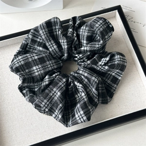 Vue détaillée d'un chouchou en tissu à carreaux noir et blanc classique sur un plateau