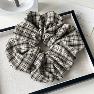 Détail d'un grand chouchou vintage à carreaux marron avec texture tissée et étiquette