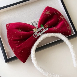 Detail of red velvet bow with Merry Christmas metal tag and soft white plush headband