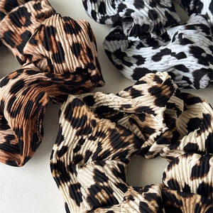 Macro detail of pleated leopard print hair scrunchies showing fabric texture and patterns