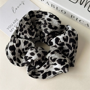 Detail of pleated leopard print hair scrunchie on a stylish lifestyle background