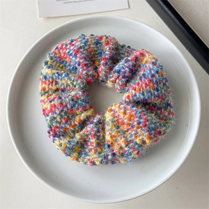 Nahaufnahme eines bunten, gestrickten Plüsch-Haargummis auf einem weißen Teller