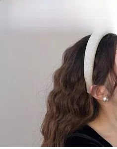 Detailed close-up of a padded light gold fabric headband on a model with wavy hair