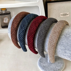 Close-up of five colorful textured tweed padded headbands on a grey velvet display stand