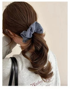 Close-up of a smoky grey velvet scrunchie holding a low ponytail in soft lighting