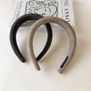 Close-up of thick wool fabric headbands in dark grey and beige with hand made labels