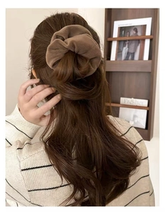 Brown plush velvet scrunchie worn on hair in a cozy indoor lifestyle setting