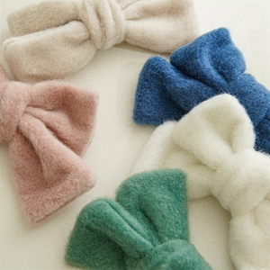 Gros plan de cinq pinces à cheveux noeuds en peluche beige rose bleu blanc et vert