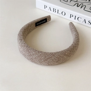 Detail of wool fabric headband with handmade label next to art book on beige background