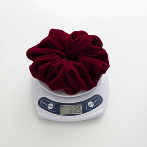 Detailed view of heavy burgundy velvet scrunchie weighing 33.5g on a digital scale