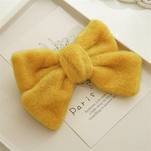 Gros plan d'une pince à cheveux n'ud en peluche jaune vif avec une texture douce et soyeuse