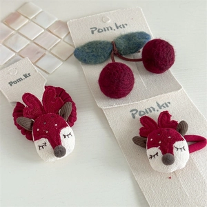 Detailed close-up of handmade red felt cherry hair clip and festive reindeer hair accessory