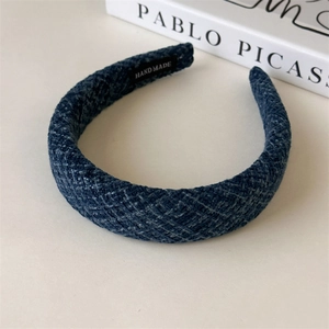 Detail of navy blue tweed headband with handmade label and artistic book background