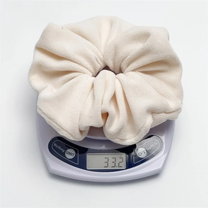 Macro detail of a plush cream velvet scrunchie weighing 33.2g on a digital scale