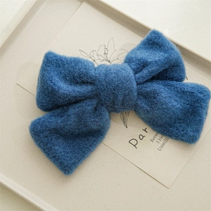 Détail d'une pince à cheveux nœud en peluche bleu foncé avec texture de laine douce