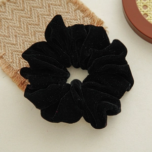 Close-up of black velvet scrunchie with subtle shimmer and soft ruffled texture detail