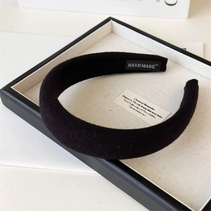Detail of black thick sponge headband with knitted twill texture and handmade label