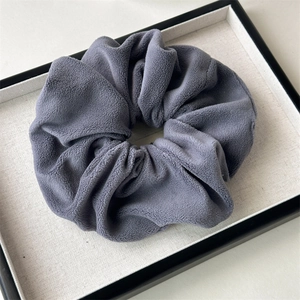 Detailed view of a dark grey plush scrunchie showing thick fleece fabric and soft texture