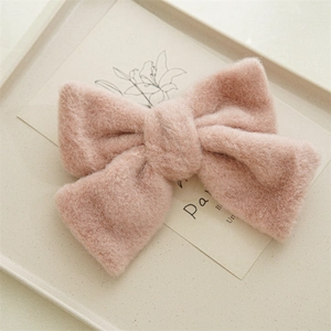 Détail d'une pince à cheveux nœud rose en peluche avec texture douce en fausse fourrure