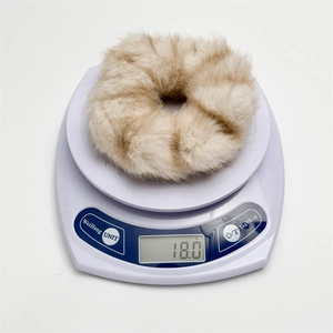 Gros plan d'un chouchou en fausse fourrure beige sur balance indiquant 18,0g