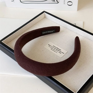 Macro shot of brown ribbed knit wide headband with a black Hand Made woven label