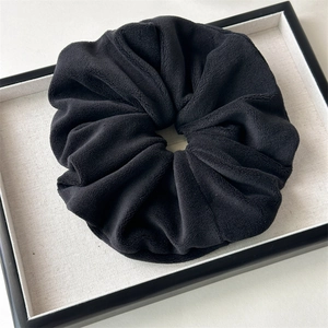Detail of premium black plush oversized scrunchie showing soft fleece texture and folds
