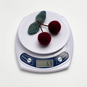 Detailed view of handmade cherry wool felt hair clip on a digital scale weighing 6.9 grams