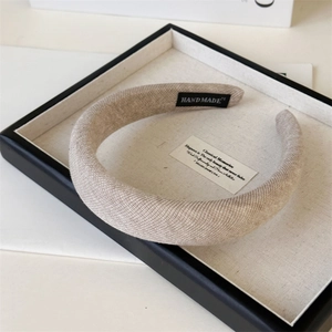 Close-up of oatmeal fabric headband with hand-made label in minimalist display tray