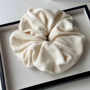 Close-up of soft plush milk white velvet scrunchie on a display tray for winter hairstyles