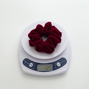 Elegant deep red velvet scrunchie for women weighing 12.0g on a scale for quality check