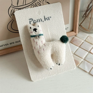 Detailed macro view of white felt alpaca hair clip with green collar and silver bell