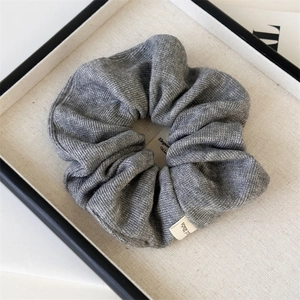 Macro shot of grey ribbed knit scrunchie with Hand Made label on a display tray