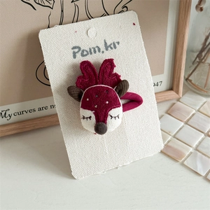 Detail of a handmade 3D reindeer hair clip in burgundy knit for girls' Christmas styling