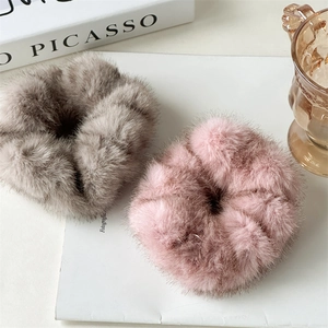 Détail de chouchous en fausse fourrure pelucheuse grise et rose sur fond de magazine chic