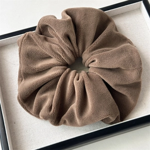 Detail of plush coffee brown velvet hair scrunchie with soft coral fleece texture