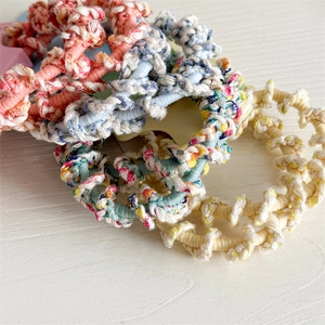 Lot de deux élastiques à cheveux tissés en spirale aux tons pastel sur bois blanc