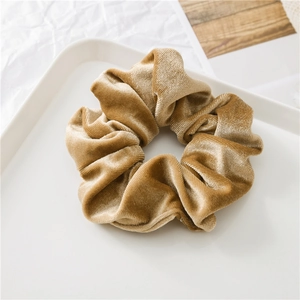 Macro dello scrunchie in velluto oro champagne che mostra la trama morbida del tessuto