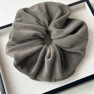 Close-up of a large dark grey plush scrunchie with soft fleece texture in a display tray