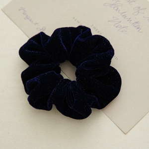 Detail of navy velvet scrunchie with glitter texture and elegant pearl accent