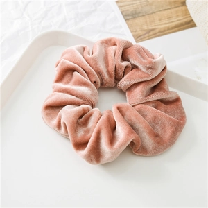 Dettaglio dell'elastico per capelli in velluto rosa cipria su un vassoio bianco