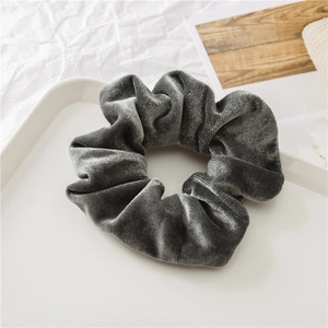 Dettaglio di scrunchie in velluto grigio su vassoio bianco con texture morbida e design pieghe