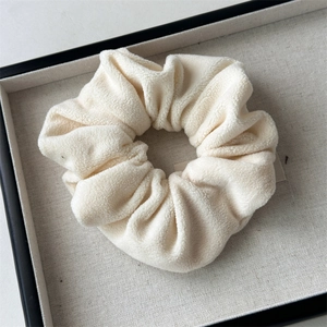 Close-up of soft beige plush scrunchie showing the fluffy texture and elastic design